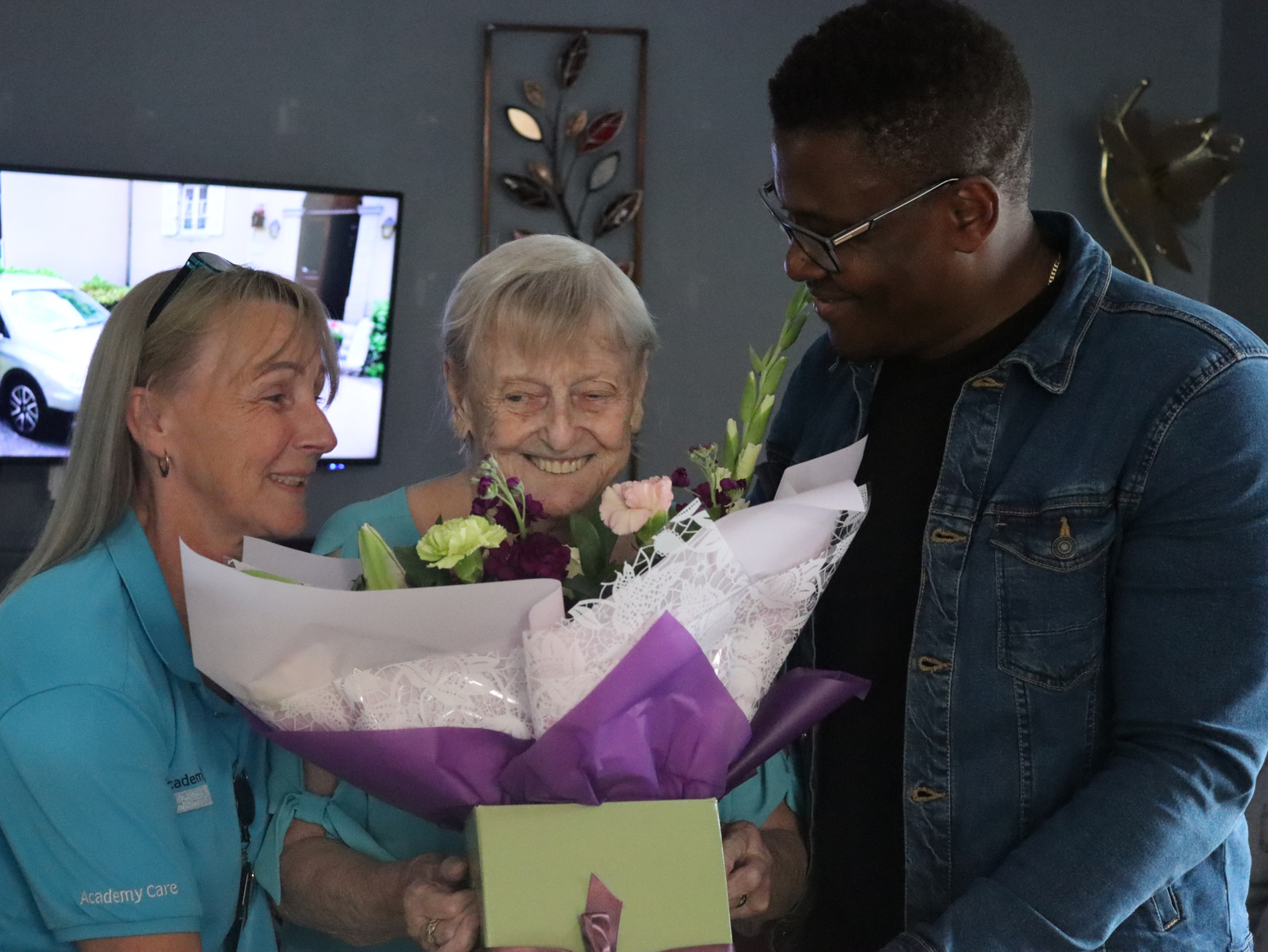 Two members of Academy Care gifting flowers to a Client